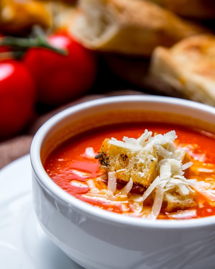 portrait shooting tomato soup with crackers and cheese tomatoes and bread on the table